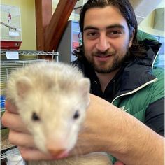 a man holding an oposs in his hand and smiling at the camera while he is petting it