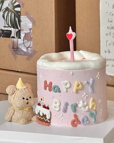 a pink birthday cake sitting on top of a table next to a small teddy bear