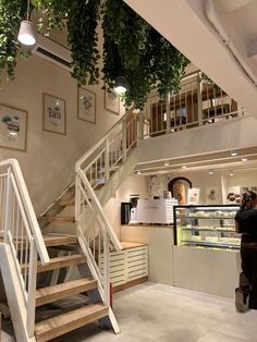 a store with stairs and plants hanging from it's ceiling, next to a coffee shop counter