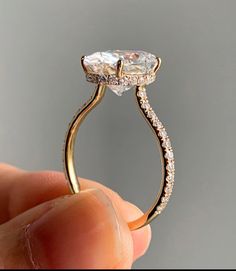 a close up of a person holding a ring with an oval shaped diamond on it