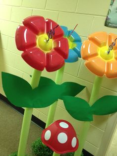 three plastic flower sculptures in the shape of flowers and toad's feet with grass growing between them