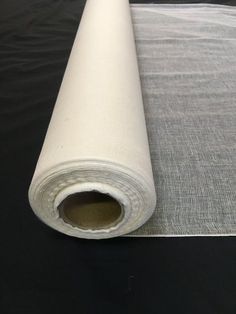 a roll of white fabric sitting on top of a black table next to a piece of cloth