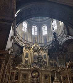 the interior of an old church with gold and white decorations on the alter, chandelier and windows