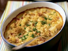 a casserole dish filled with macaroni and cheese, garnished with parsley