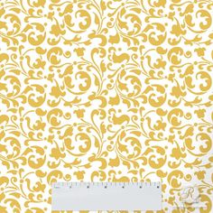 a yellow and white wallpaper with an ornate design on it's side, next to a ruler