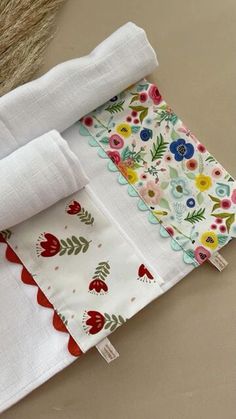 two folded napkins on top of each other with flowers and leaves printed on them