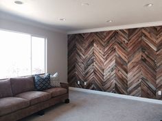 a living room with a brown couch and wooden wall