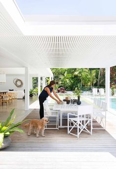 a woman standing at a table with a dog in front of her on the deck