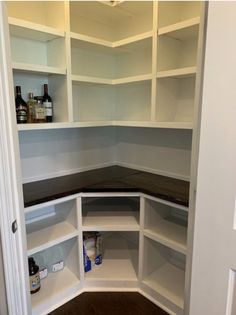 an empty pantry with white shelves and wood flooring