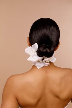 the back of a woman's head with a white flower in her left hair