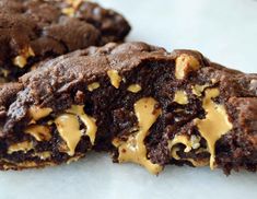 chocolate cookies with peanut butter drizzled on them are sitting on a white surface