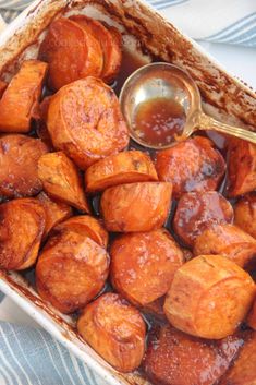 sweet potatoes with sauce in a dish on a tablecloth next to a spoon and napkin