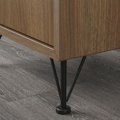 a wooden cabinet with black metal legs and an open drawer on one side, next to a gray tile floor