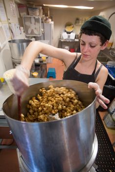 a woman stirring food in a large pot