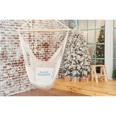 a white hammock hanging from the side of a brick wall next to a christmas tree