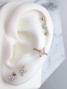 an ear with three different types of piercings on top of it, sitting next to a marble surface