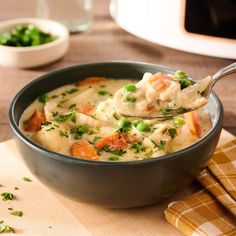 a bowl of chicken and dumpling soup on a wooden table with a spoon in it