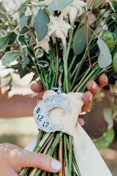 a person holding a bunch of flowers with the number thirteen on it's ribbon