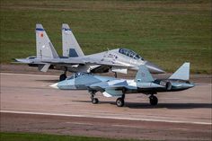 two fighter jets sitting on top of an airport tarmac next to another jet plane