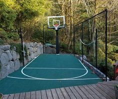 an outdoor basketball court surrounded by trees and rocks