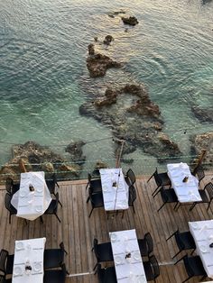 an outdoor dining area overlooking the ocean with tables and chairs set up for two people