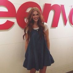 a woman standing in front of a sign that says lenovo on the wall behind her