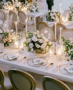 a table set with white flowers and candles for a formal dinner or wedding reception in an elegant setting