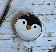 a painted penguin ornament next to a pencil