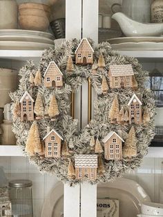 a wreath is hanging on the front door of a house with trees and houses painted on it