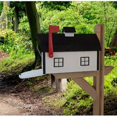 a house shaped mailbox sitting on top of a wooden post