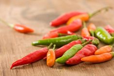 several different colored peppers on a wooden surface