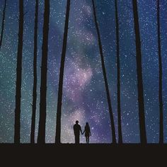 two people are standing in the woods looking at the stars