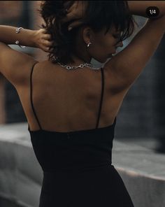 a woman in a black dress is holding her arm behind her head