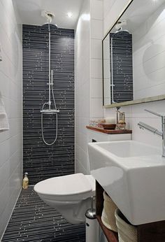 a bathroom with a toilet, sink and shower in it's stall area next to a mirror