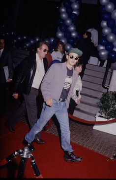 a man walking down a red carpet with balloons in the background