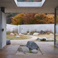 an outdoor area with rocks, grass and trees in the background is seen through glass doors