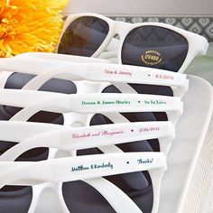 four pairs of sunglasses are sitting on a white plate next to a yellow sunflower