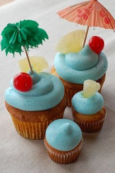 three cupcakes with blue frosting and cherries on top, each topped with an umbrella