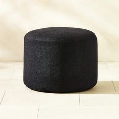 a black ottoman sitting on top of a white tiled floor