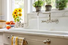 a kitchen sink with sunflowers in the window