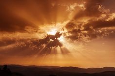 the sun shines brightly through clouds in this photo taken on top of a mountain