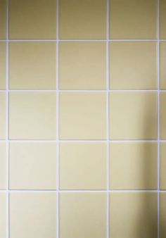 a white toilet sitting next to a yellow tiled wall in a bathroom with no shower curtain