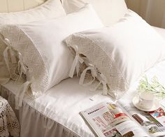 a bed with white sheets and pillows on top of it next to a cup of coffee