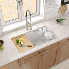 a kitchen sink sitting under a window next to a cutting board