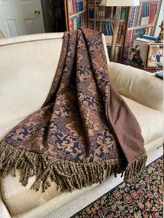 a couch with a blanket on top of it in front of a bookshelf