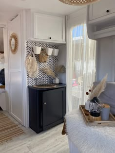 a kitchen with white cabinets and black counter top next to a door that leads to a bedroom