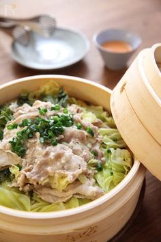 a close up of a bowl of food on a table with chopsticks and sauce