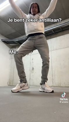 a man standing on one leg with his hands up in the air while wearing white sneakers