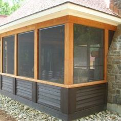 a screened porch in front of a stone building