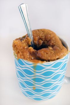 a cookie in a cup with spoons sticking out of it's center, on a white surface